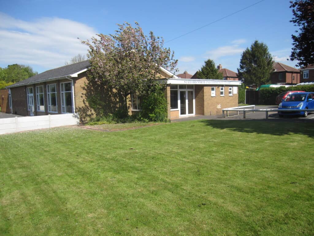 a mown lawn with a one story building and a tree